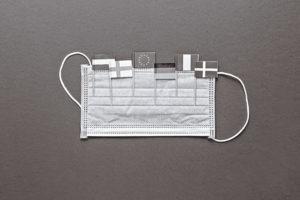 A surgical face mask with small national flags tucked into it
